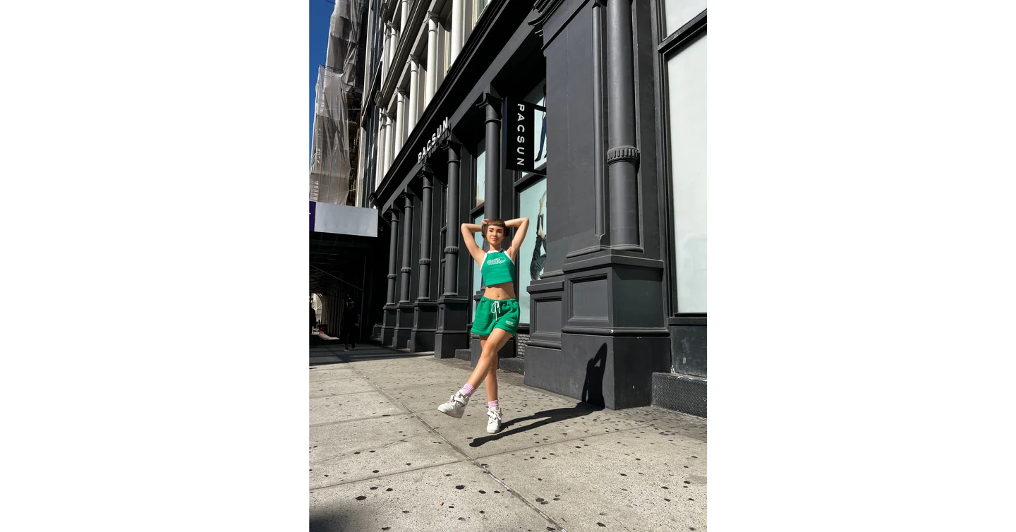 Miquela outside the Pacsun storefront, shown full-length in a tank top and shorts. The source's white side panels are retained.